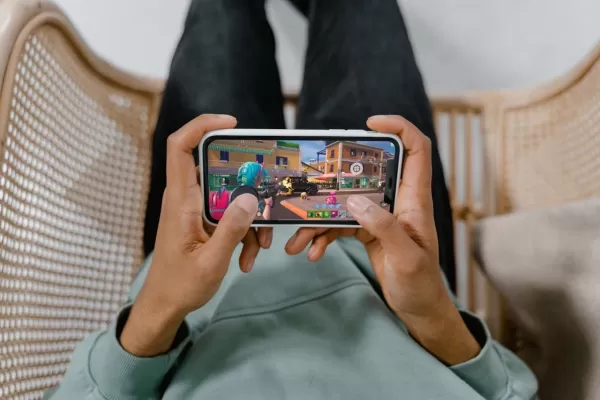 a pair of hands holding a phone playing fortnite with a magnetic trigger attached to the phone